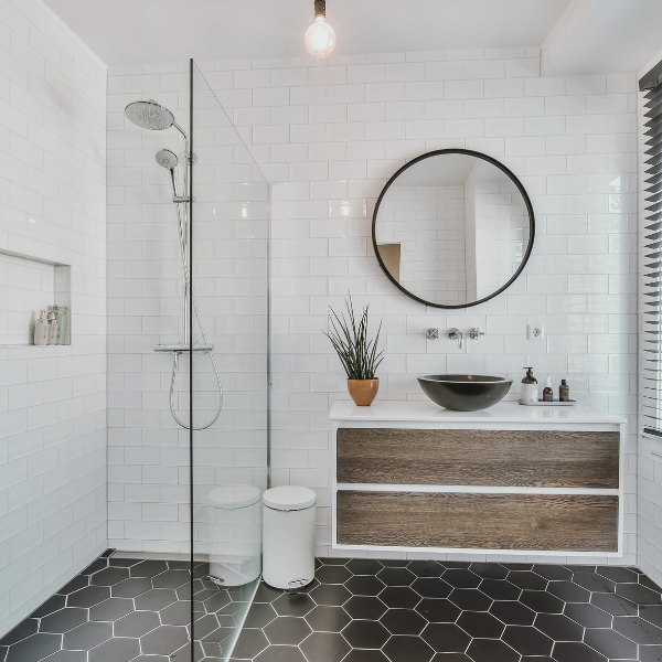 new vanity with circular mirror and glass enclosed shower